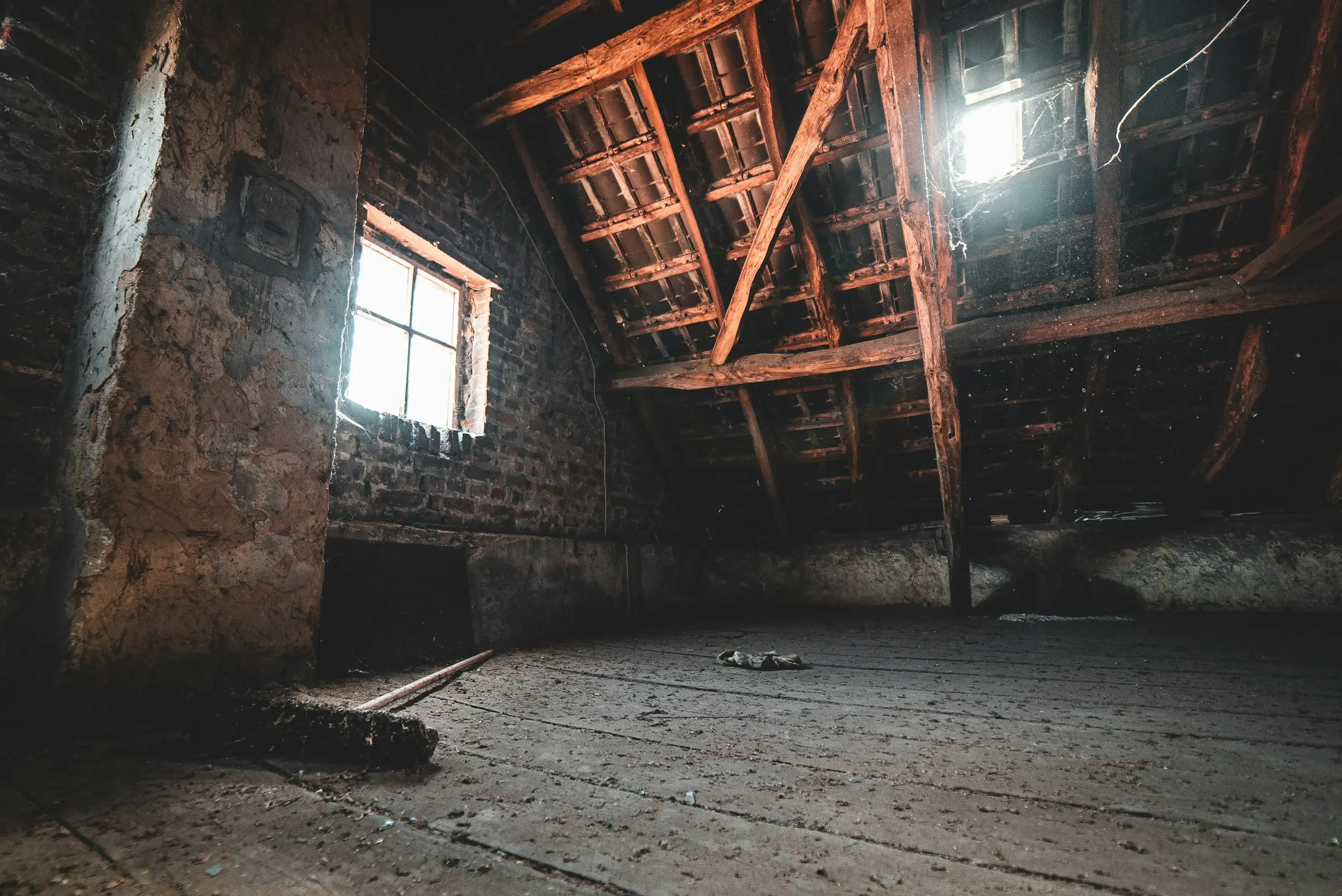 An empty attic with exposed rafters and daylight